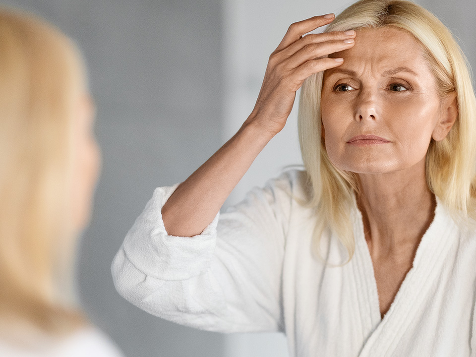 Frau betrachtet ihre Haut im Spiegel