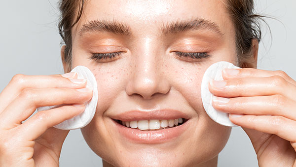 Frau reinigt ihr Gesicht mit Wattepads