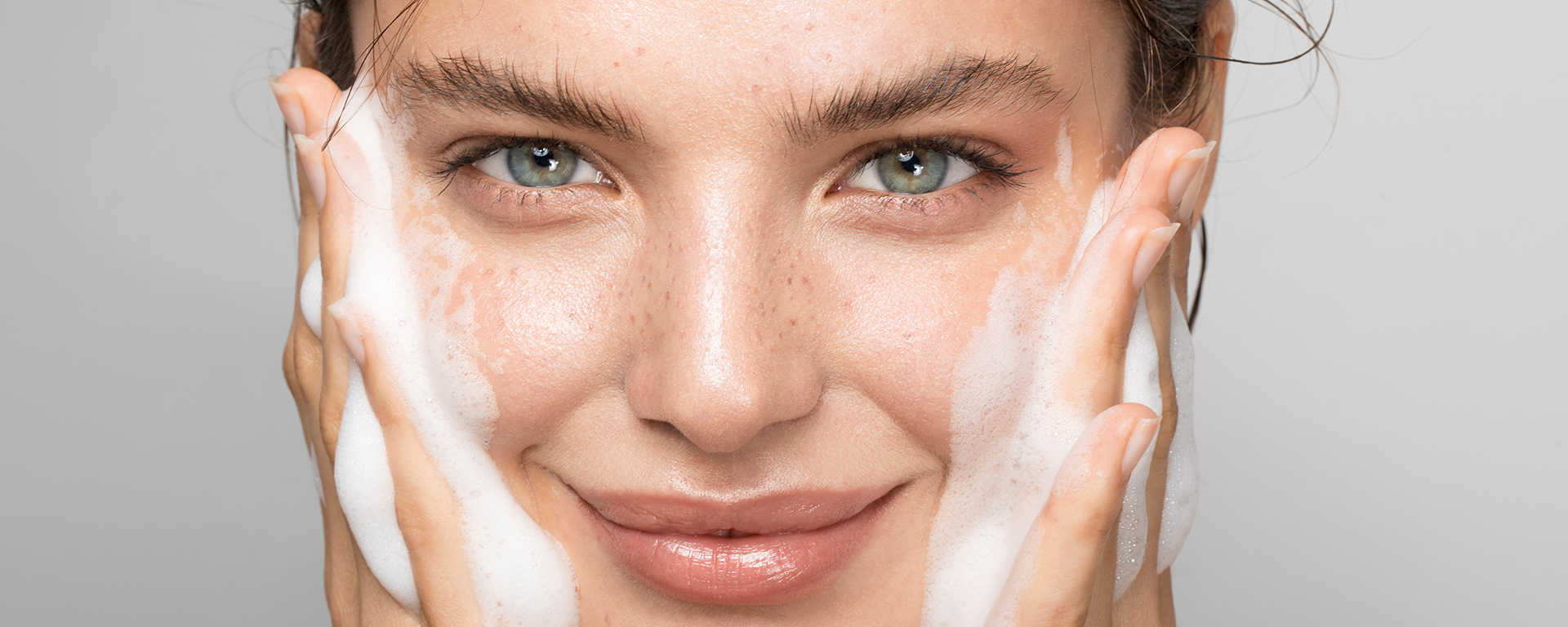 Frau reinigt ihr Gesicht mit Schaum
