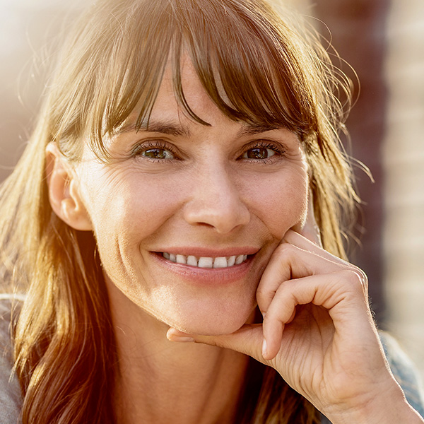 Eine Frau im Gegenlicht lächelt in die Kamera