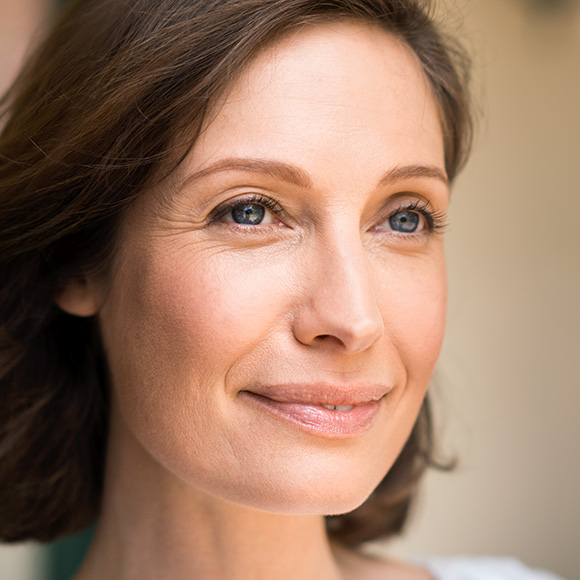 Frau mit wehenden Haaren blickt lächelnd in die Ferne