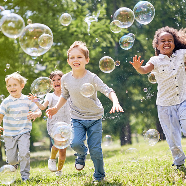 Kinder laufen in Seifenblasen