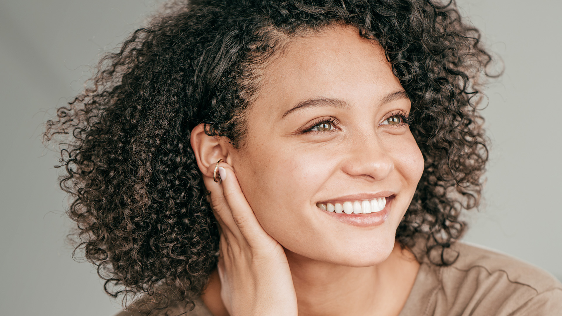 Eine junge, lächelnde Frau mit lockigem Haar.