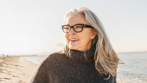 Eine Frau mit Brille steht am Strand und genießt die Sonne